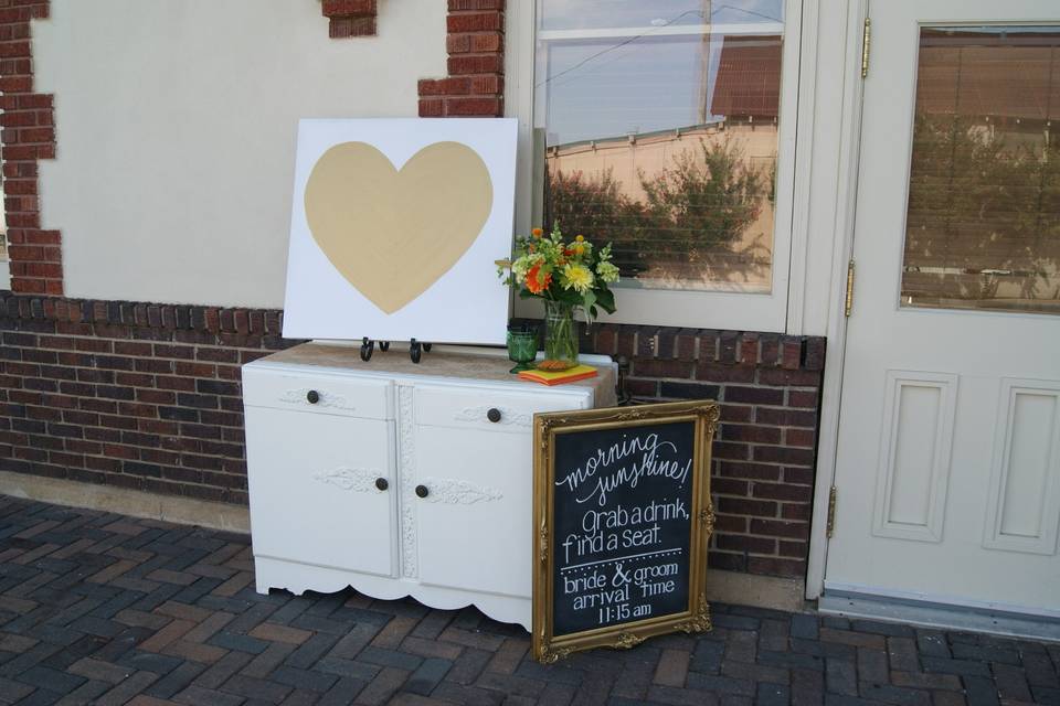 entry of a wedding reception- chalkboard, shabby chic buffet, floral, and a canvas sign-in board located at the train depot in Ardmore