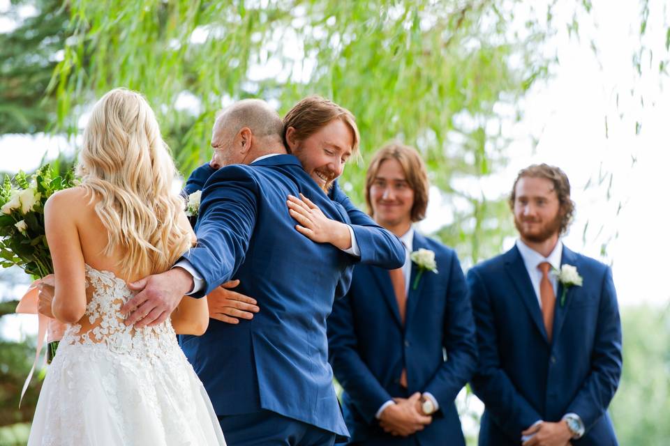 Father and groom hug