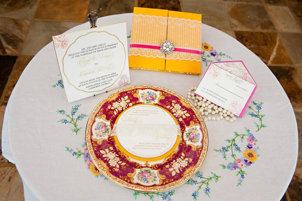 Display of wedding stationary on vintage china and hand embroidered linens
