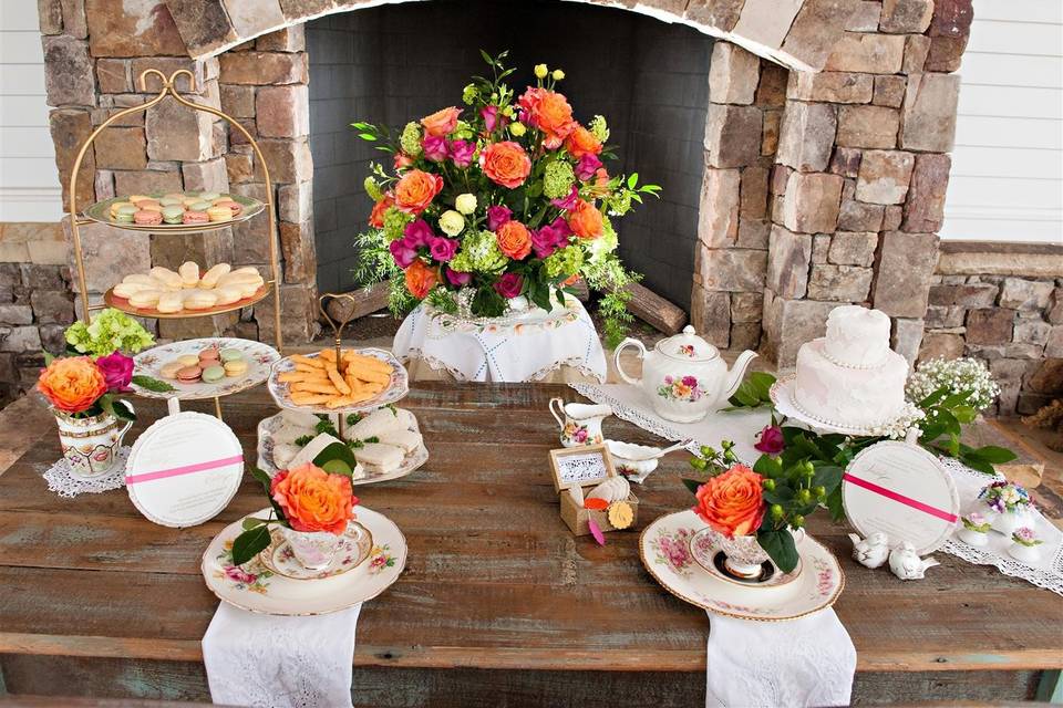 Lovely farm table displayed in front of rustic fireplace showcases vintage fine china