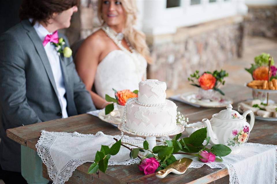 Happy couple view their sweetheart table spread with vintage fine china