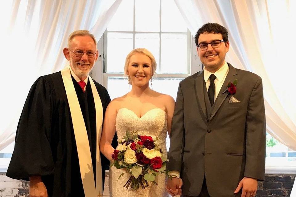 Newlyweds with the reverend at the reception