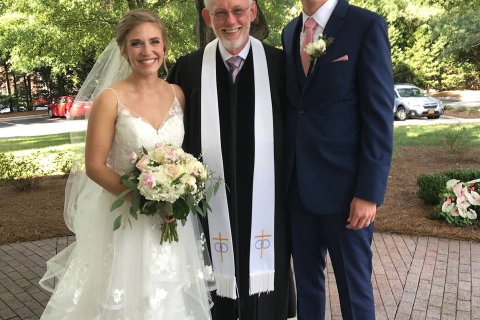 Newlyweds with the reverend at the reception