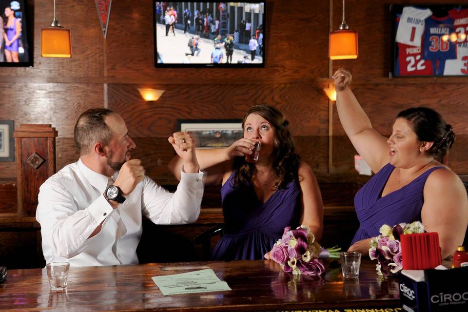 The maid of honor chugs her shot to the delight of the groom and bridesmaid in Detroit, Michigan.