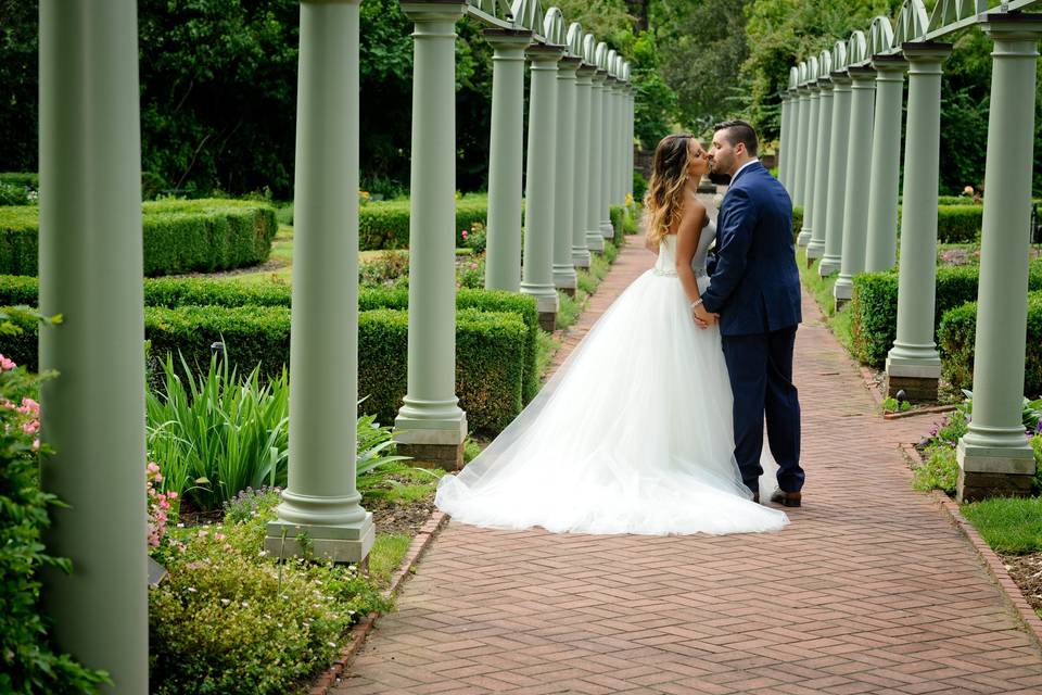 A couple kiss in the gardens of Meadowbrook Hall after their wedding.