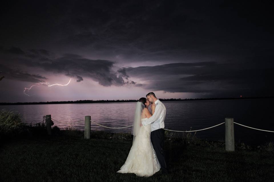 A couple kiss lakeside during a summer lightening storm in Michigan.