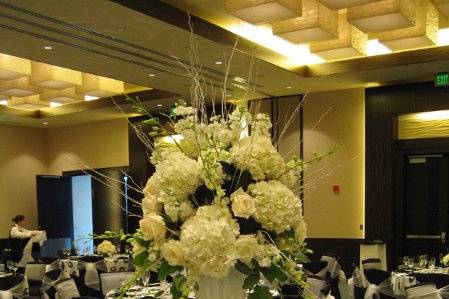 Tall trupmpet vase with light. All white hydrangea, roses, orchids & sticks