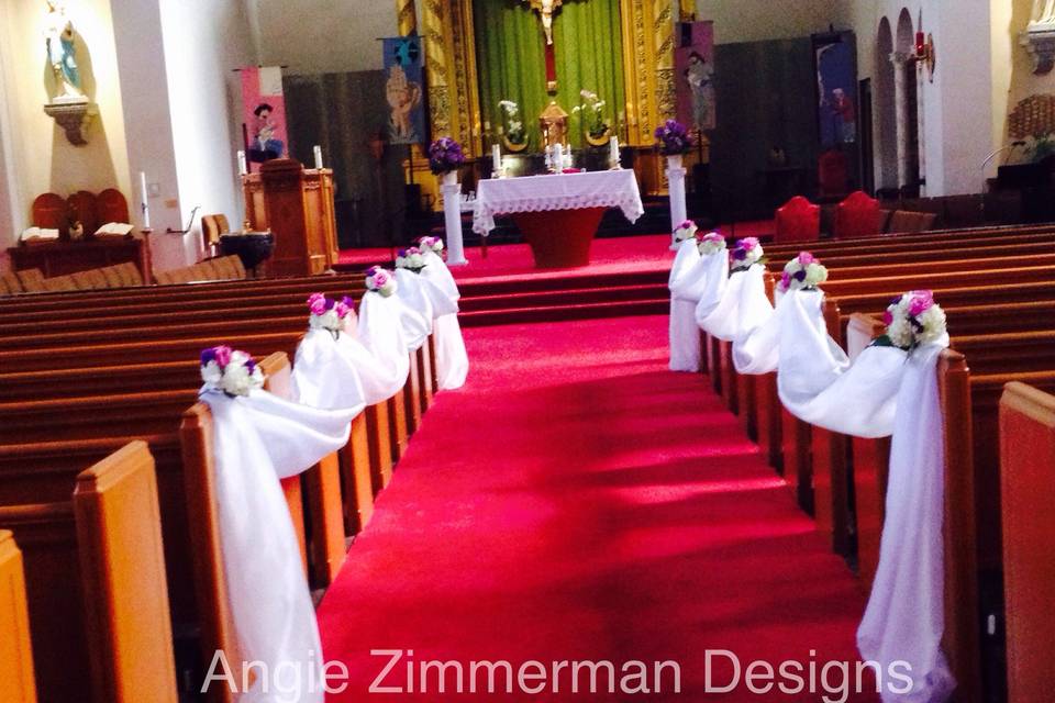 Decorated pews/aisle in a Catholic church.  #ceremonydecor #aisledecor #pewflowers #angiezimmermandesigns