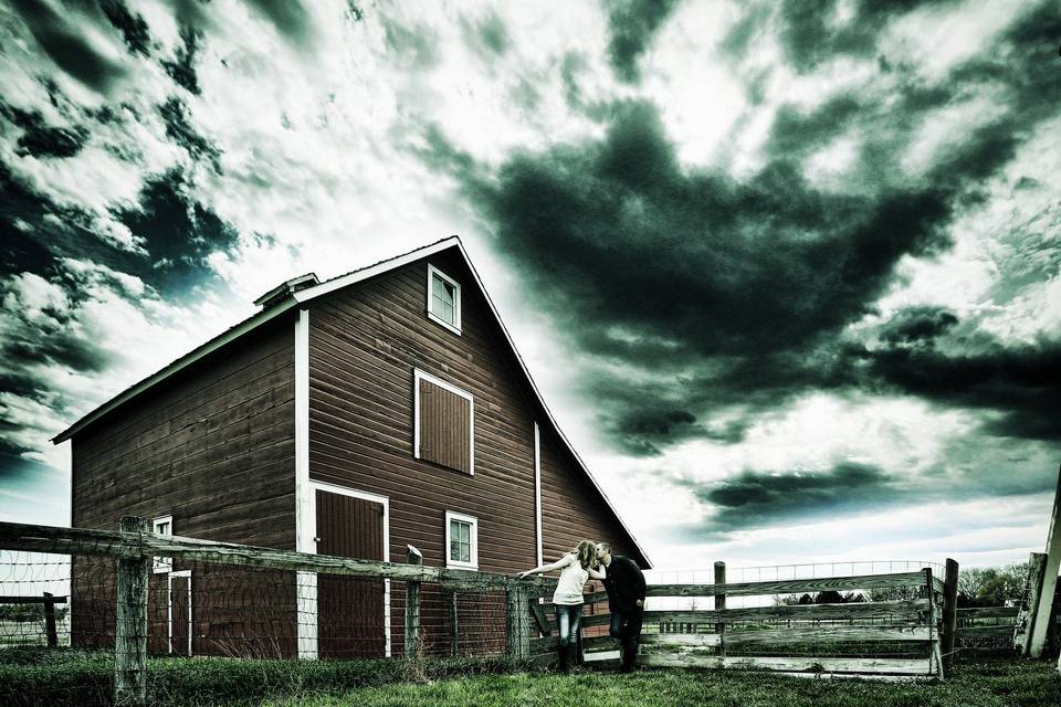 Couple pose outside of a classic red barn