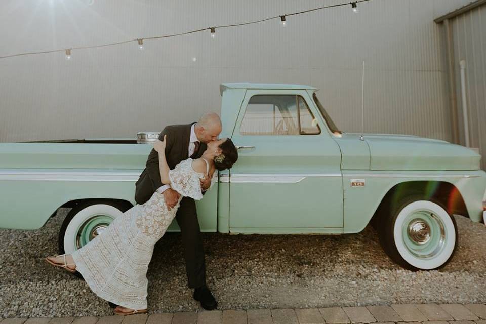 Newlyweds kiss by the car