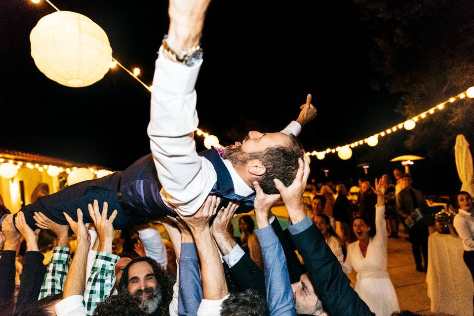 Groom lifted up and carried by groomsmen--crowd surfing at his wedding reception.