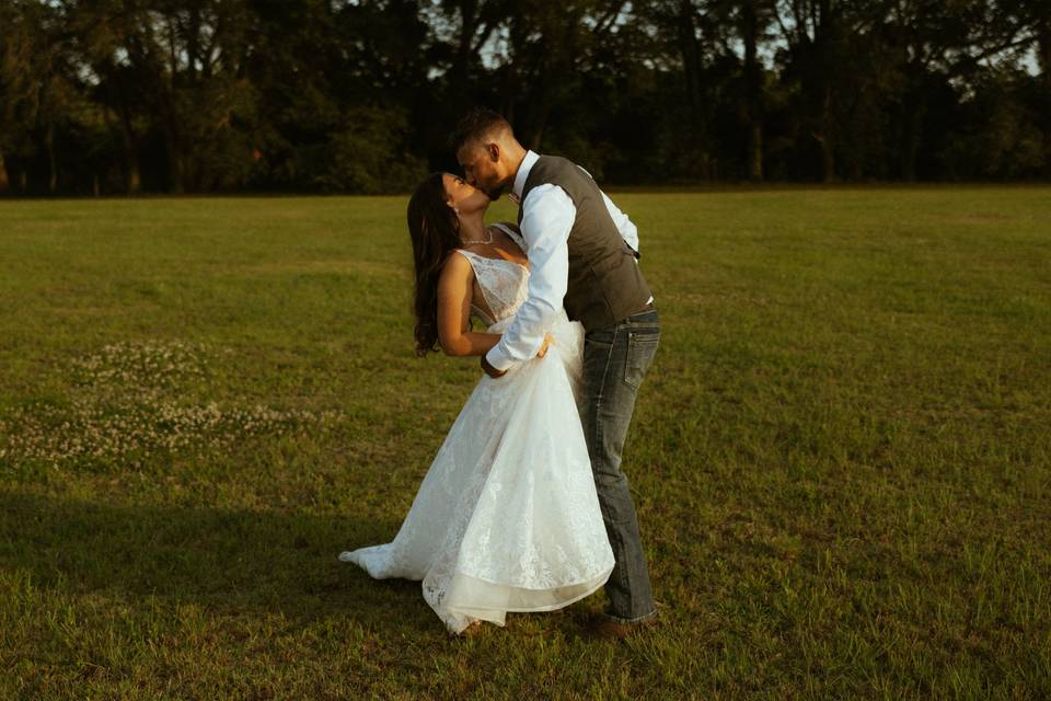 Bride & groom kissing in field