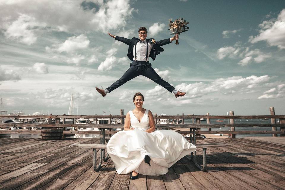 A groom jumping over a bride