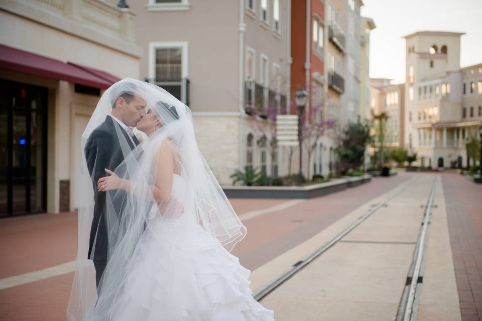 Bride and Groom pause for a kiss along the Eilan's Trolley Tracks with a background setting of a Tuscan Village