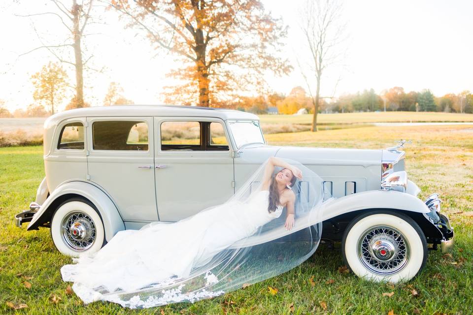 Bride laying on vintage car