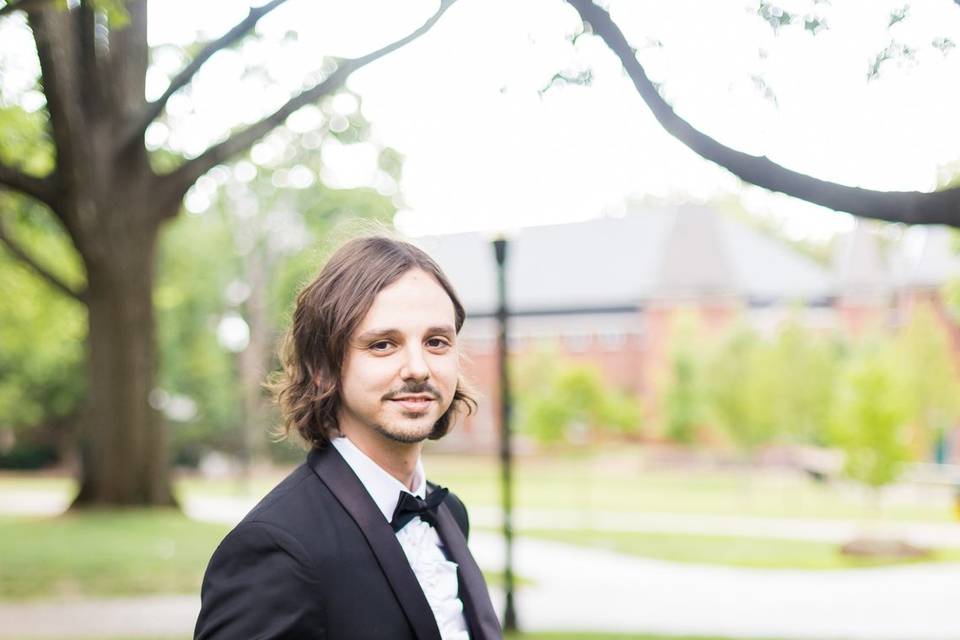 Groom buttoning his tux.