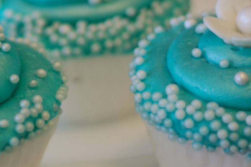 Turquoise cupcakes with gum paste flowers and pearls.