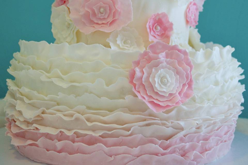 Pink and white ruffle ombre cake with pretty flowers.