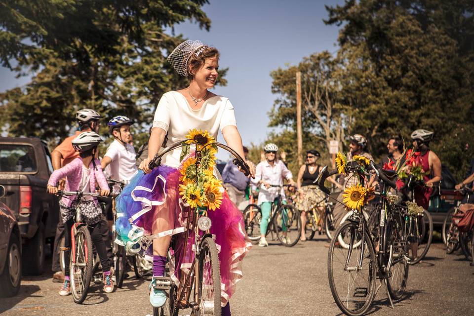 Beautiful bride with a custom made dress about to take off on her post ceremony bike ride down main street Port Townsend, Wa.