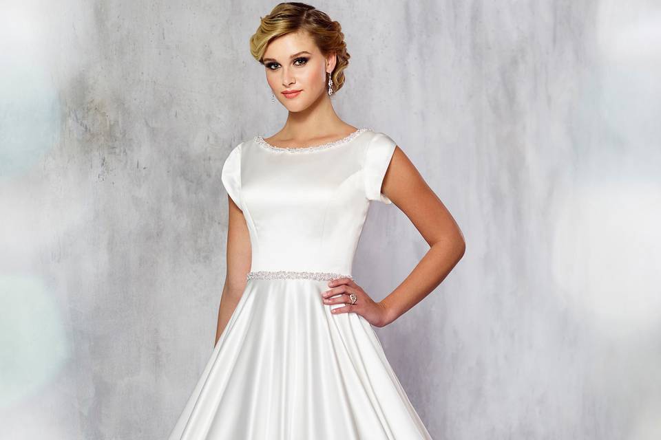 Tr21716satin ball gown with tulip cap sleeves, bateau neckline and natural waist trimmed with pearl beading. Sizes 0 – 20, 18w – 26w colors: ivory, white