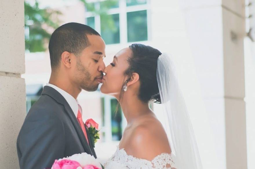 Newlyweds kissing by the tree