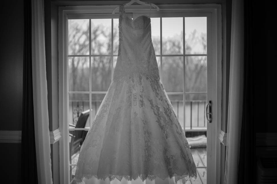 Bridal dress hanging beside window