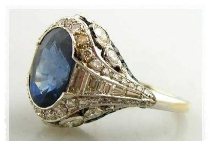 Art Deco sapphire and diamond ring centrally set with a faceted oval cut sapphire, weighing approximately 4.75cts, mounted atop sixty six diamonds weighing 2.75cts, and thirty eight calibre cut sapphire totaling 1.50cts in a setting crafted in 4.1dwt platinum. Size 5 1/4.
