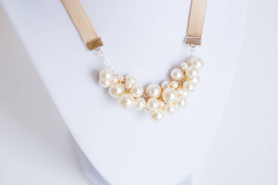 Handcrafted bridal necklace of ivory Swarovski pearls with tiny peach/pink freshwater pearl accents and blush/champagne satin ribbon for adjustable length. As seen in Style Unveiled, Fall 2014.Findings: Silver Plated Closure: Ribbon tie Handcrafted to order at our studio in Baltimore, MD.