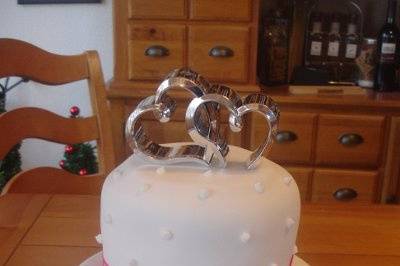 A pretty fondant cake with a metal keepsake topper, wrapped in satin ribbon