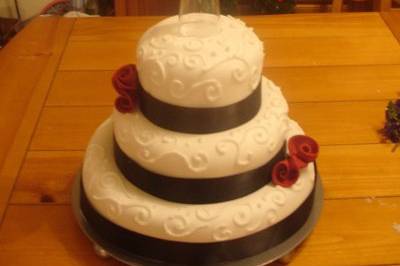 A fondant design with white piping, whimsical roses and the 4th tier balanced on a champange glass.