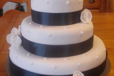 A fondant design wrapped in black ribbon with white roses