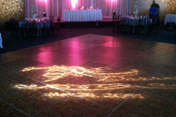 Custom design with the couple's names and date projected onto the dance floor.  We also have fabric with colored lights setup behind the head table.