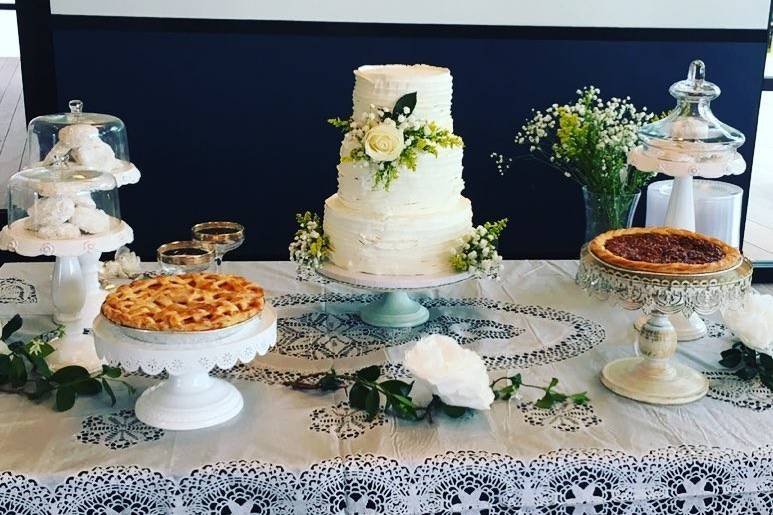 Three tiered cake with italian buttercream: lemon raspberry, red velvet and fresh pineapple filled. Mexican wedding cookies, peach pie and bourbon pecan pie all by Wyeth Patisserie