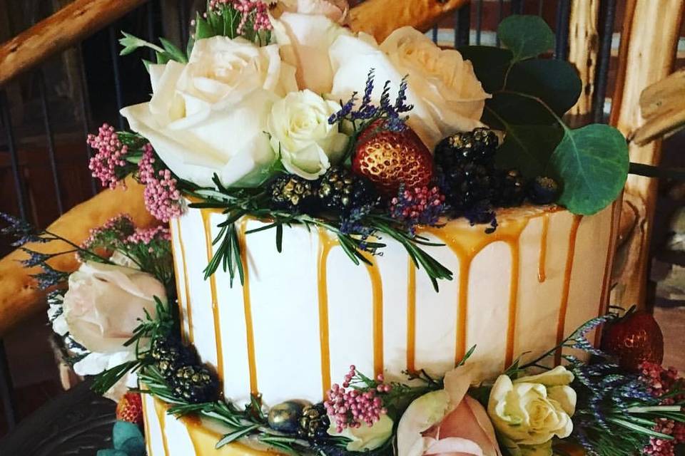 Vanilla cake filled and drizzled with salted caramel finished with fresh flowers, greenery and fruit.