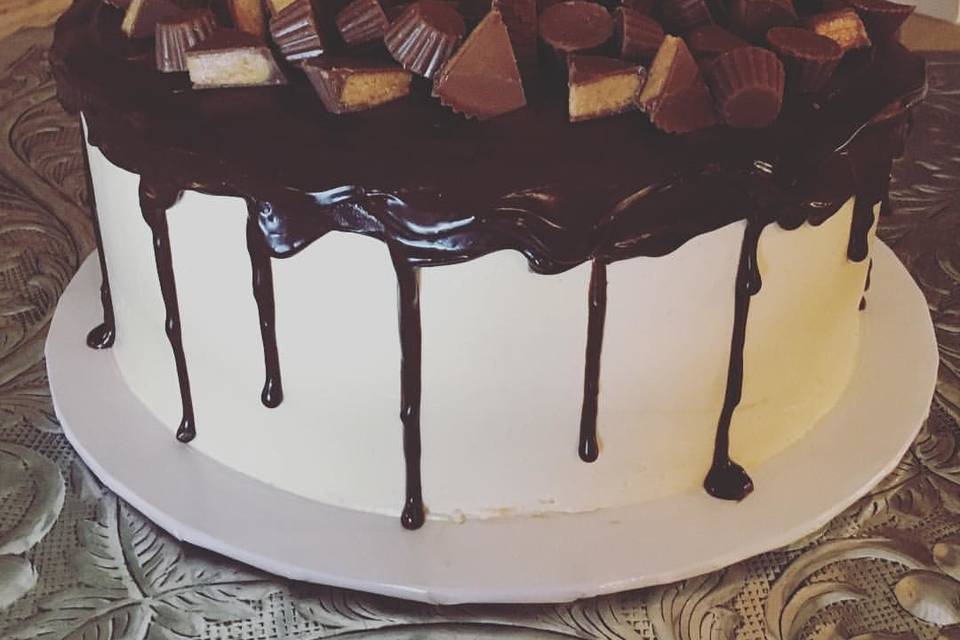 Chocolate cake with peanut butter buttercream with chocolate ganache and reeses peanut butter cups in between the layers and on top.