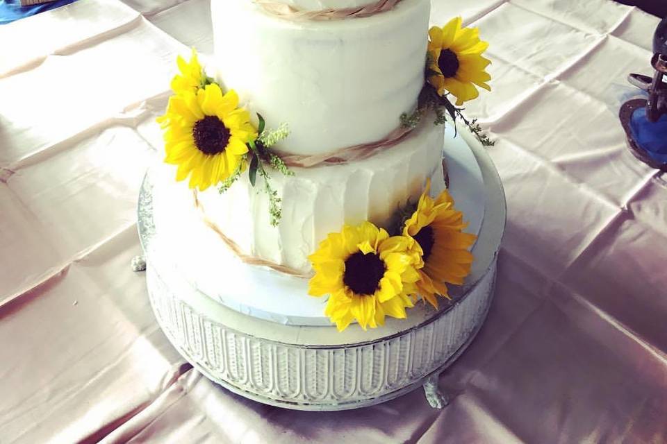 Vanilla cake filled and drizzled with salted caramel finished with fresh flowers, greenery and fruit.