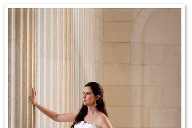 An elegant bridal portrait amidst large beige columns, in her wedding dress.