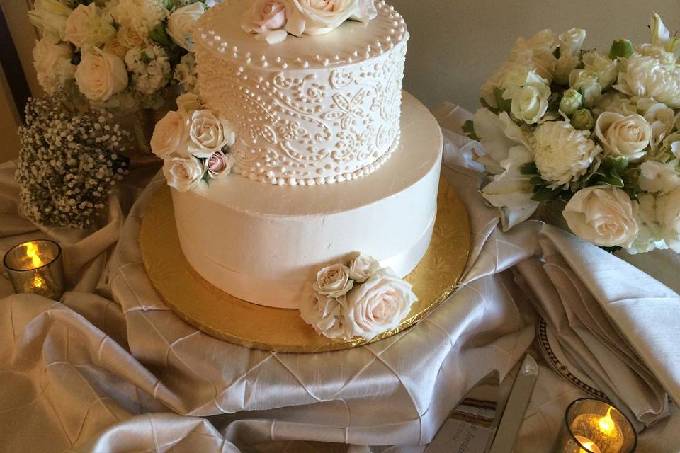 Cake with scrollwork/paisley icing in ivory and fresh flowers