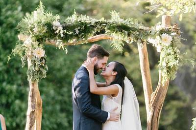 Couple kiss under wedding arch