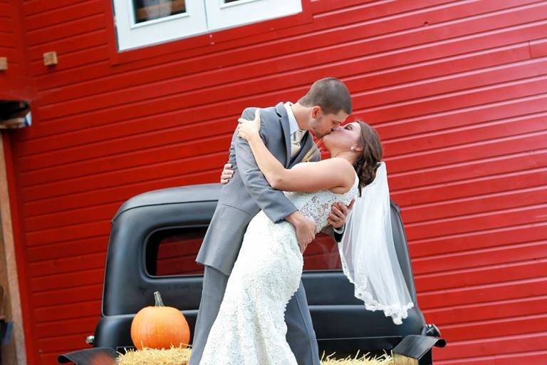 Wedding kiss on top of truck | Gown: Rebecca Ingram