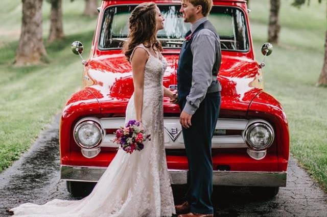 Newlyweds in front of red wedding car