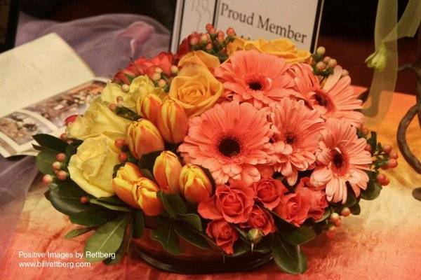 Grouped flowers in a low, massed centerpiece of vibrant oranges and peaches.
