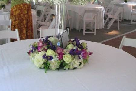 Baby's Breath cloud on a silver pedestal, surrounded by a wreath of flowers in purples, pinks and cream