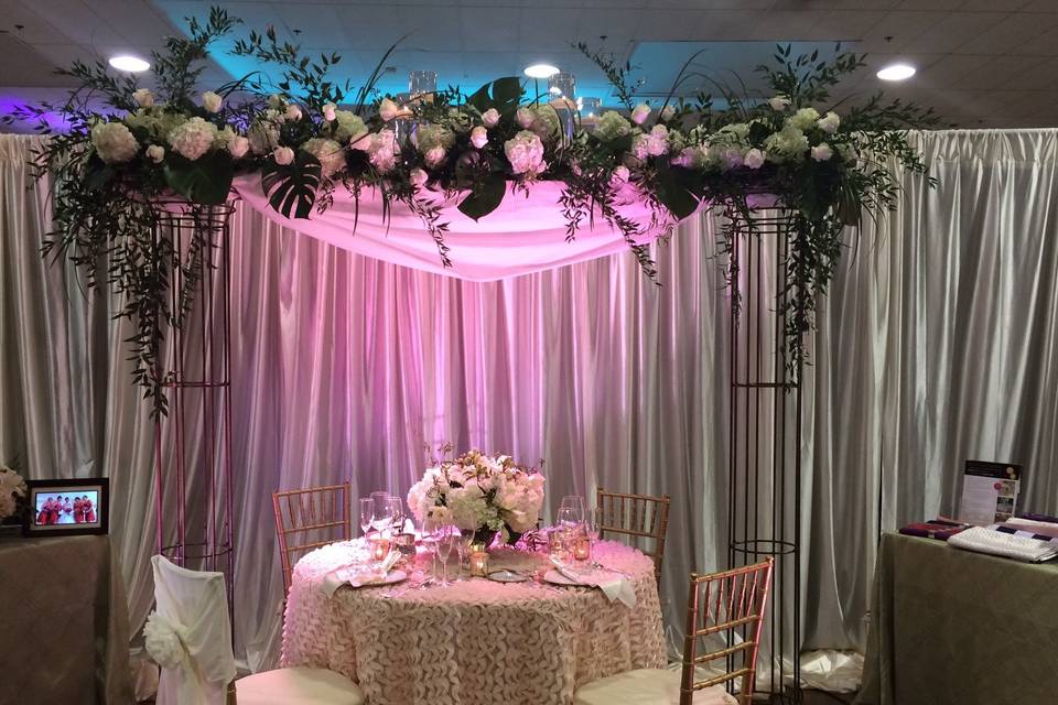 Wonderful arbor, useful in so many ways!  Here it's framing the sweetheart table, might also be used to focus the ceremony, as an entrance to an event or to enhance a beautiful cake!
Show at a Bridal show.