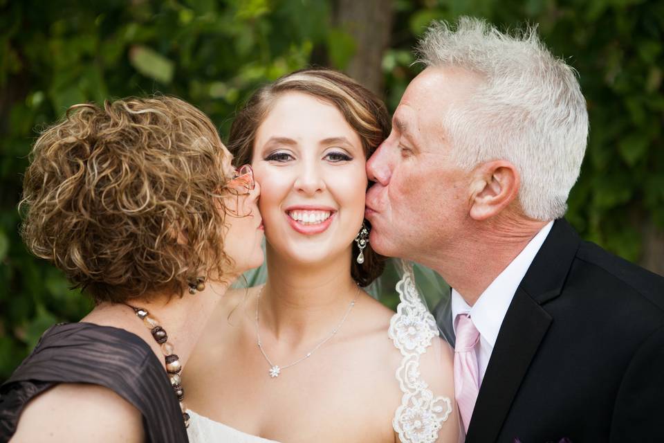 Parents kissing bride