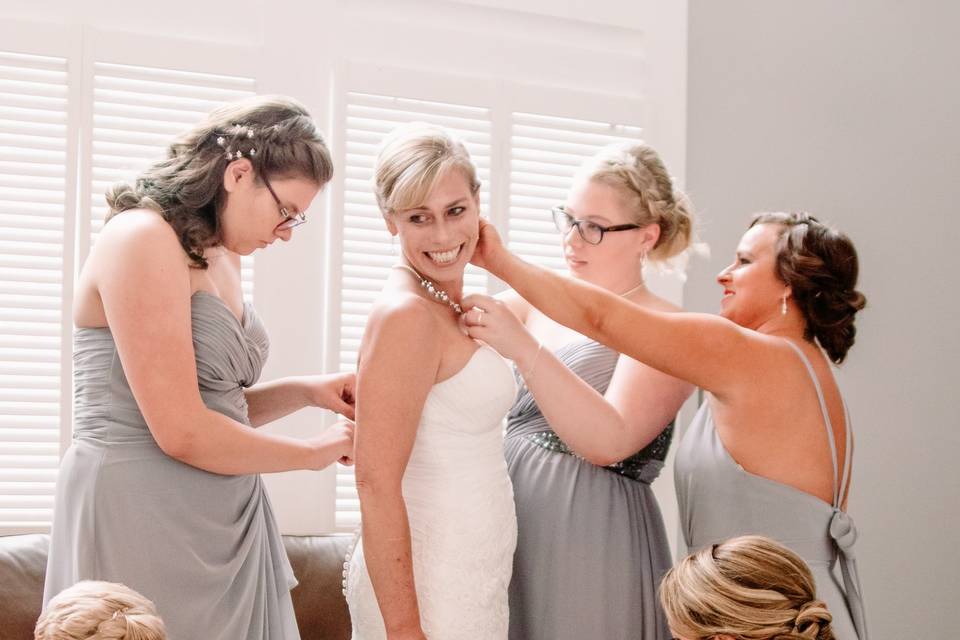 Bridesmaid help bride in dress