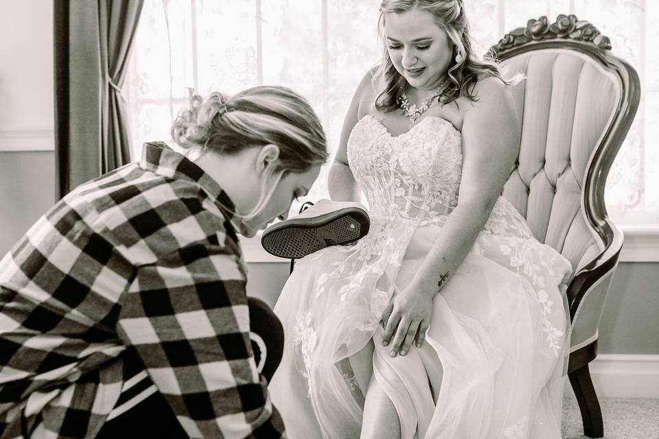 Bridesmaid tying brides shoes