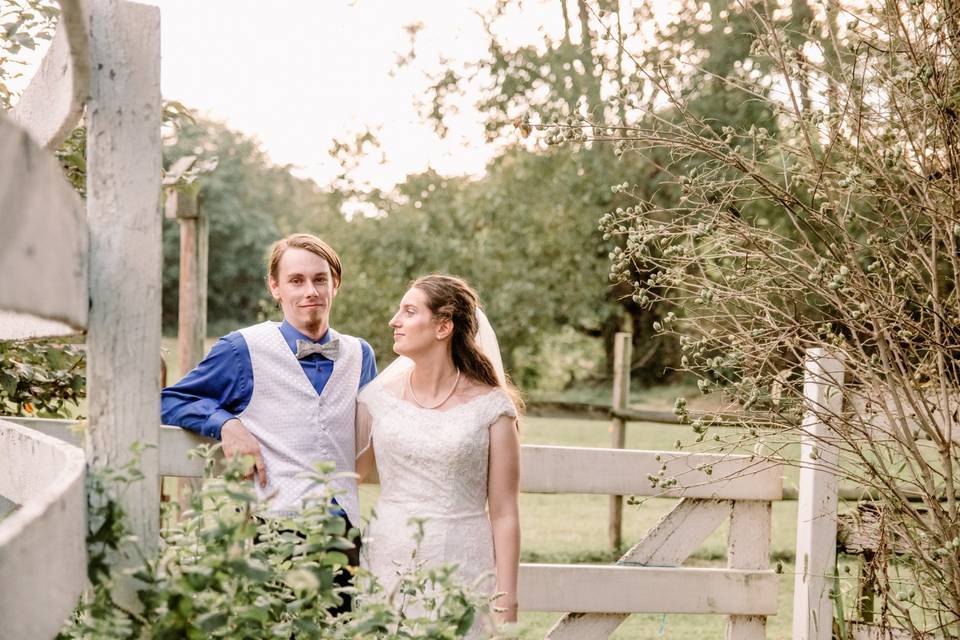 Bride looks at groom by fence