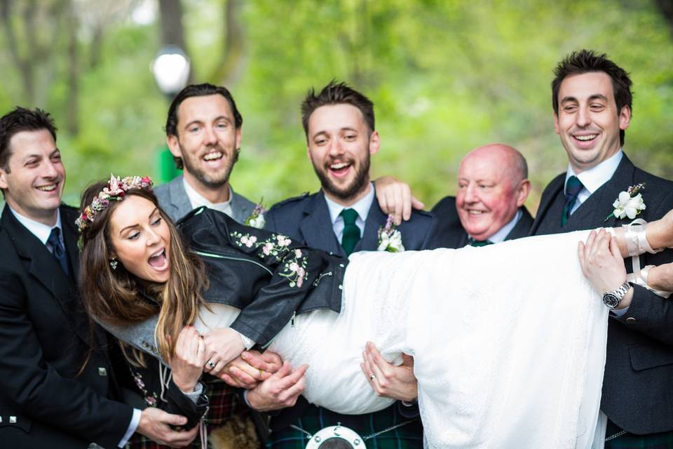 Groom and groomsmen carrying the bride