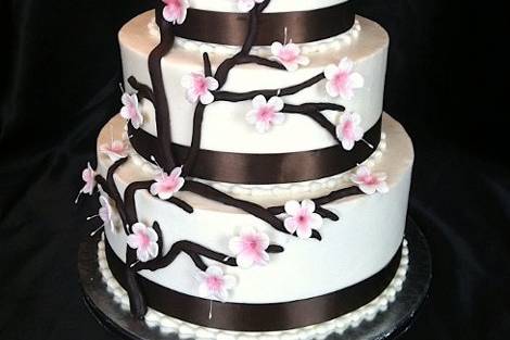 Springtime abounds with delicate gumpaste cherry blossoms that grace dark chocolate fondant branches. Chocolate brown satin ribbon adds a finishing touch.